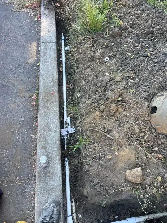New PVC irrigation line laid in a trench along a curb in Mountain View