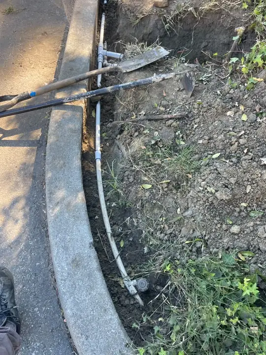 Trenching along a planter curb to replace PVC sprinkler lines in Mountain View
